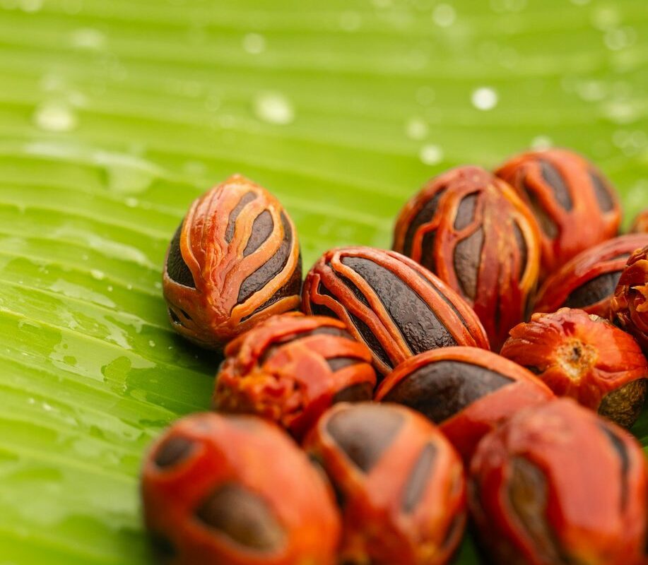 Whole nutmeg seeds wrapped in red mace on a banana leaf